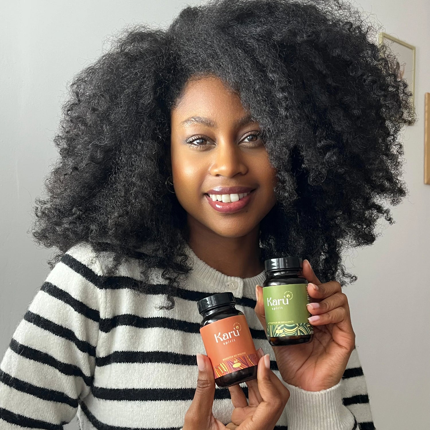 transformation femme cheveux frisés tenant les compléments alimentaire pour cheveux